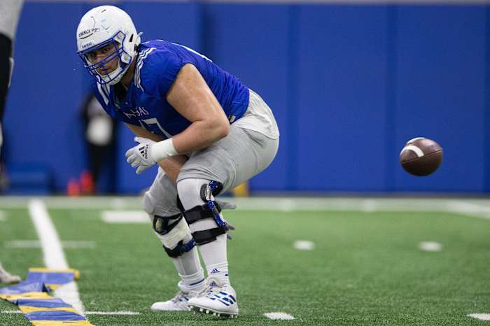 Kansas redshirt senior offensive lineman Dominick Puni (67) hikes the ball during practice Thursday.